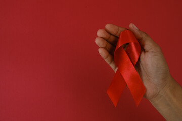 woman Holding Red Ribbon For December World Aids Day Isolated On red Background. Healthcare Concept