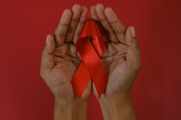 woman Holding Red Ribbon For December World Aids Day Isolated On red Background. Healthcare Concept