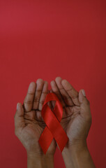 woman Holding Red Ribbon For December World Aids Day Isolated On red Background. Healthcare Concept
