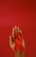 woman Holding Red Ribbon For December World Aids Day Isolated On red Background. Healthcare Concept