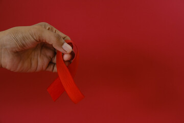 woman Holding Red Ribbon For December World Aids Day Isolated On red Background. Healthcare Concept