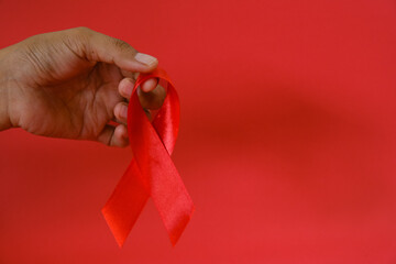woman Holding Red Ribbon For December World Aids Day Isolated On red Background. Healthcare Concept
