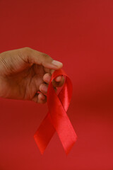 woman Holding Red Ribbon For December World Aids Day Isolated On red Background. Healthcare Concept