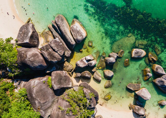 A stunning top-down aerial (flat lay) view of Tanjung Tinggi Beach, Belitung. Giant granite boulders, white sand, and clear turquoise water create a beautiful natural abstract pattern.