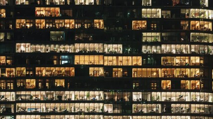 Seamless day-to-night timelapse of modern glass skyscraper facade. Office windows light up in evening. Flickering lights urban life, architecture, business in contemporary city. Zooming out transition