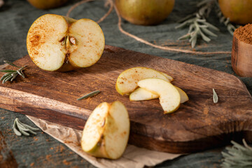 A rustic still life with sliced russet apples sprinkled with cinnamon on a wooden cutting board, evoking a cozy, autumnal mood