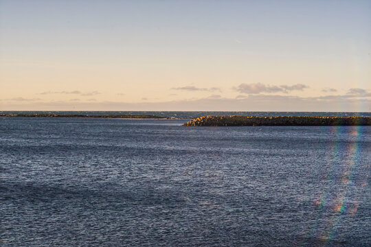 Calm sea with rocky breakwater at sunset