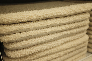 Soft , fluffy and comfy seating pads for chairs. Modern and trendy chair seats for kitchen or dining room. Home decor store merchandise arranges in a pile. Textile cushions for seating.