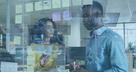 Pointing woman-mustard-top and man-blue-shirt with marker planning in tech office, glass whiteboard