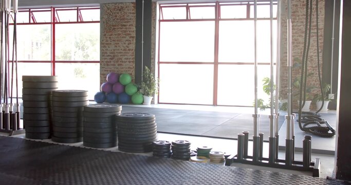 Occupying left-center foreground, stacks of bumper plates forming columns at studio gym with bars