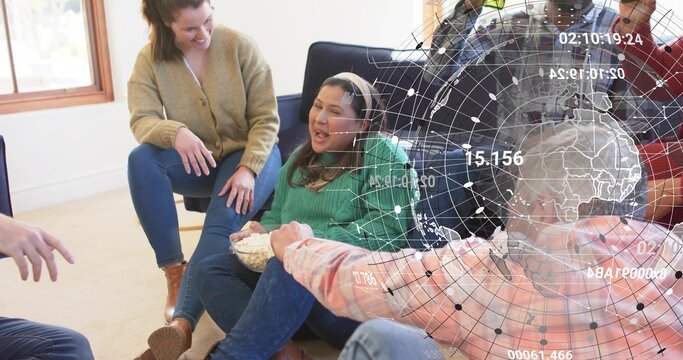 Laughing woman in green sweater holding popcorn bowl in living room, showing digital globe overlay