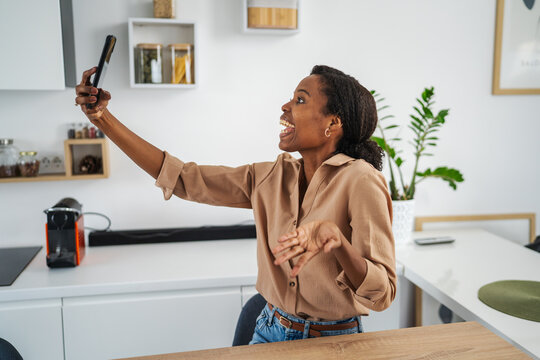Excited woman recording video call on smart phone at home
