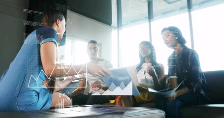 Presenting woman in blue dress leaning and showing tablet with data overlays in office lounge