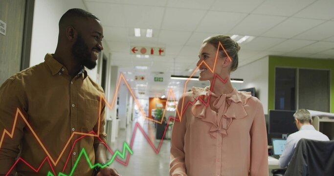 Walking two colleagues in pink blouse brown shirt, discussing data in office with overlaid graphs - Powered by Adobe