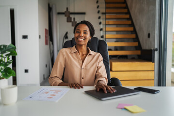 Professional african american woman working at home office desk smiling