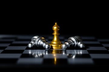 Golden chess knight with fallen silver pieces on chessboard and stock market chart background, symbolizing business strategy and financial investment.