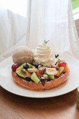 Waffles with strawberry, kiwi, banana and whipping cream in white plate on sheer curtain. Morning breakfast, dessert.