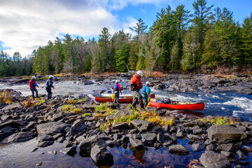 Canoe guides lining loaded boats through a shallow rapid on the Madawaska River in fall