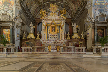 The opulent main altar of Rome's Santa Maria in Aracoeli. Gilded Baroque architecture, marble steps, and elaborate religious statuary beneath the apse. Rome, Italy
