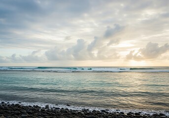Dramatic sunrise over tropical ocean waves hitting a rugged pebble beach