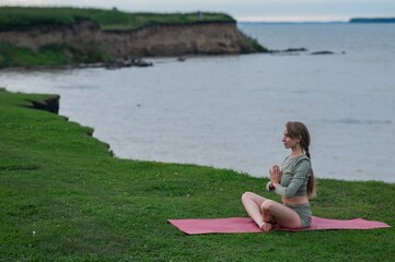 Caucasian woman doing yoga on the river bank. 