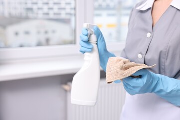 Obraz premium Cleaning window. Chambermaid with rag and detergent indoors, closeup. Space for text