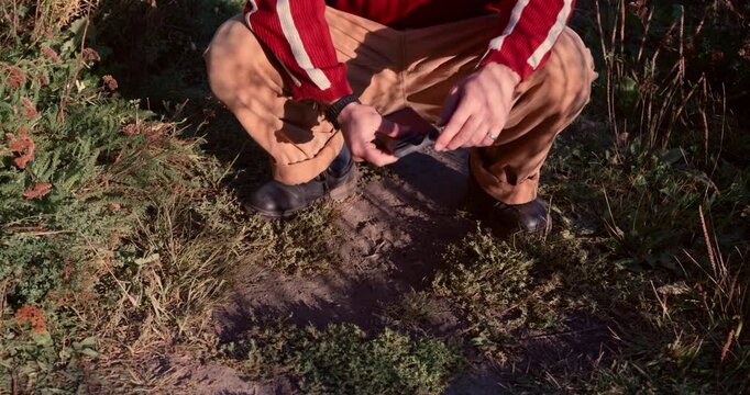 A symbolic close-up of a person burying a smartphone in the ground, representing digital detox, mindfulness, freedom from technology addiction, and reconnection with nature.