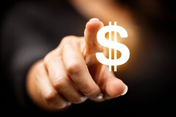 Financial Focus: A close-up view captures a hand pointing towards a glowing dollar sign. The composition creates a powerful visual representation of wealth, investment, and financial aspirations.
