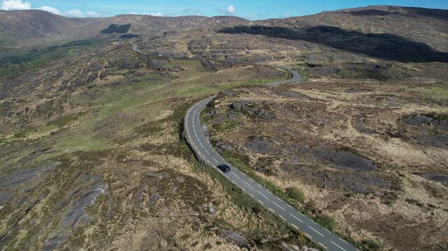 Drone Shot of Black Car Moving on Road in Caha Mountains, Ireland on Sunny Day