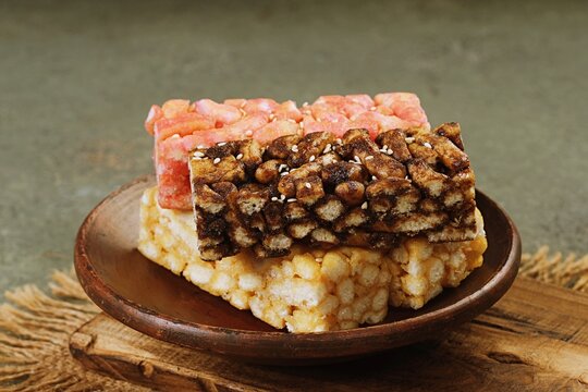Sachima in mixed flavors served on a wooden plate, highlighting texture and color of the traditional sweet snack.