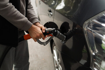 Close-up detail view of fuel autogas pump gun connected with noozle adapter to car tank to refill at car gas filling station. 