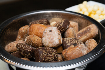 Variety of bread buns in a metal serving dish at an event