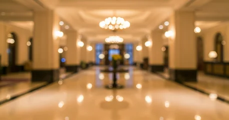 Fotobehang Hotel chique Blurred modern hotel lobby interior with warm color tones, polished surfaces, and structured lighting. Depth of field highlights architectural lines, suitable for hospitality backgrounds.  © AJI EGY TAMA