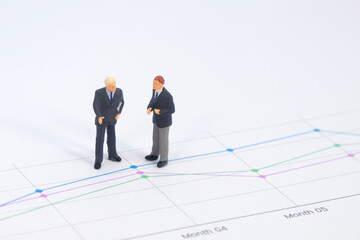 Obraz premium Miniature figures businessman standing on a graph chart financial with copy space using as background. businessman analyze achievement data