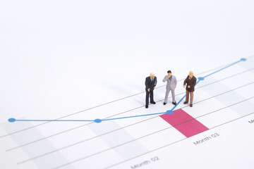 Miniature figures businessman standing on a graph chart financial with copy space using as background. businessman analyze achievement data