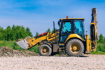 Heavy construction machinery working on land grading and gravel spreading with operator visible in cab, selective focus