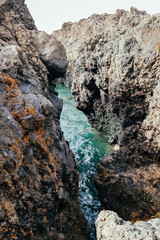 Vertical view of turquoise water in a narrow passage between rocks.