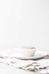 Vanilla cupcakes in a white liner on a white granite countertop, freshly baked cupcakes