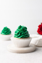 green frosting on cupcakes with a white background, cupcakes in white liners with tall buttercream swirl, green buttercream frosted cupcakes on a white background