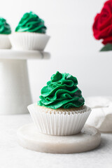 green frosting on cupcakes with a white background, cupcakes in white liners with tall buttercream swirl, green buttercream frosted cupcakes on a white background