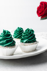green frosting on cupcakes with a white background, cupcakes in white liners with tall buttercream swirl, green buttercream frosted cupcakes on a white background
