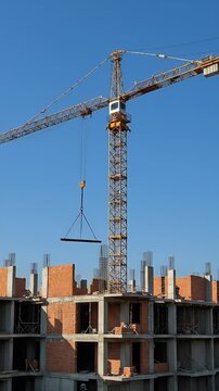 Construction Crane Lifting Materials Against Blue Sky