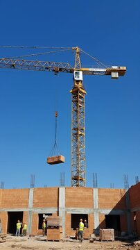Construction Crane Lifts Bricks at Sunny Building Site