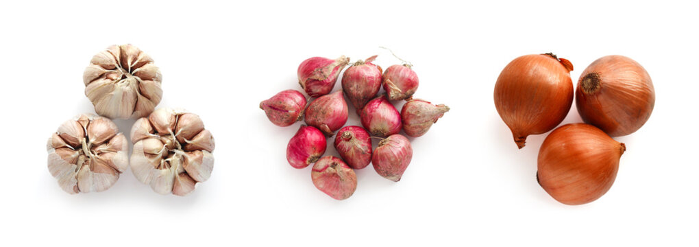 A collection set of fresh aromatic vegetables which includes garlic bulbs, cluster of red shallots, and golden brown onions. A bundle found and sold together in grocery stores and local markets.