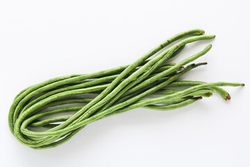A bundle of fresh, raw long green beans, also known as yardlong beans, isolated on a clean white background.