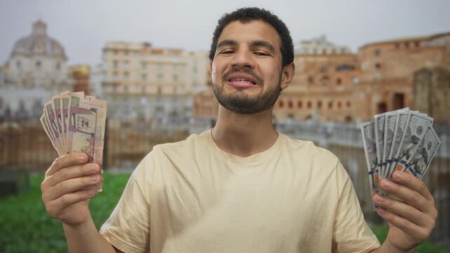 Young hispanic man holds saudi riyal and dollar banknotes in front of roman building; exchange uncertainty.