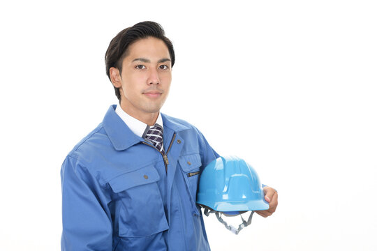 ヘルメットを持つ作業着姿の男性