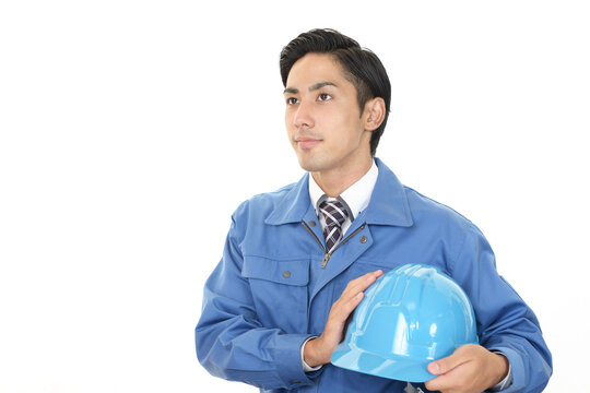 ヘルメットを持つ作業着姿の男性