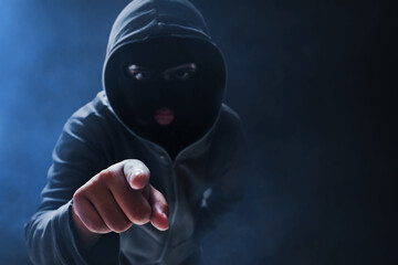 Hacker in hoodie with mask on dark background