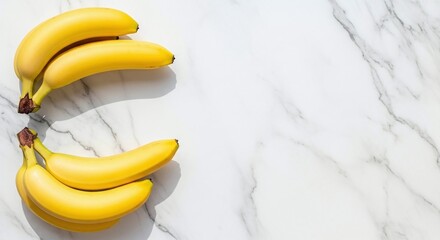 A still life of two bunches of yellow bananas on a white marble surface with soft shadows and bright lighting
